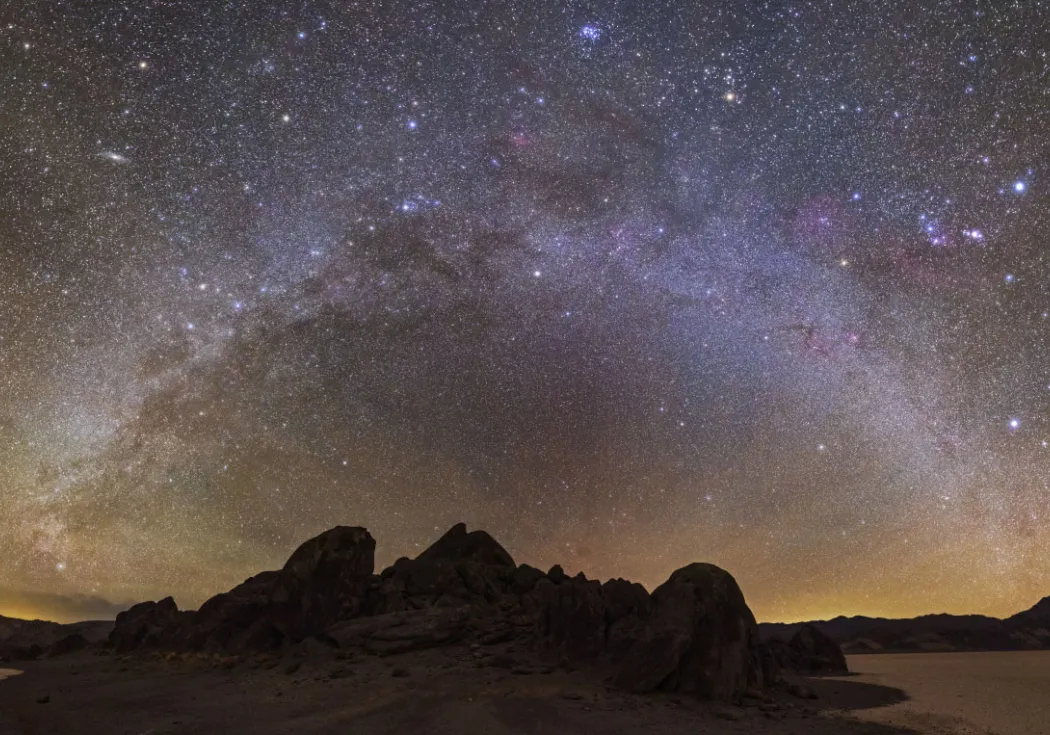 a bright halo of stars over a dark landscape 