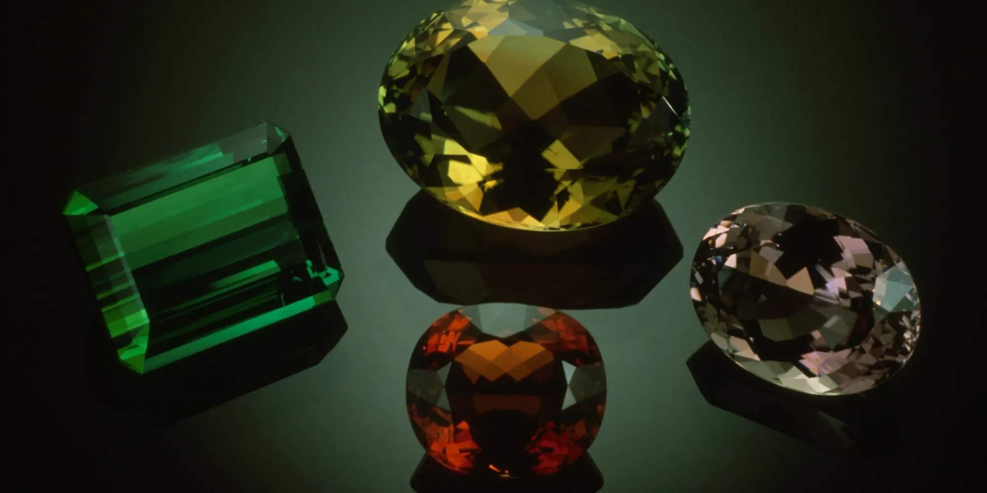 four colorful (green, yellow, red, and pink) gems on black background 