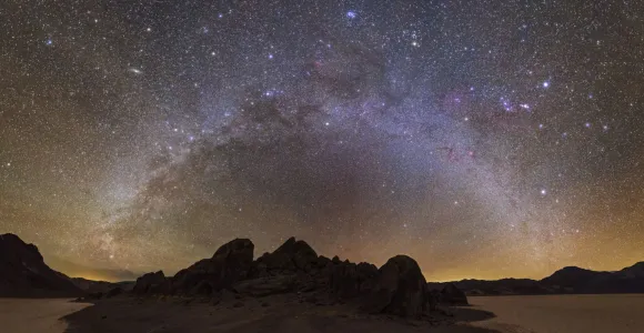 a bright halo of stars over a dark landscape 