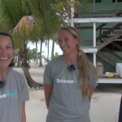 Two women in Science How t-shirts and a man in a blue t-shirt standing in front of a building and palm trees with the ocean in the background