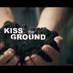 Two hands holding some black dirt, with the words Kiss the Ground superimposed on it