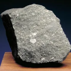 Allende Meteorite - a rock with sharp edges displayed on a wood surface