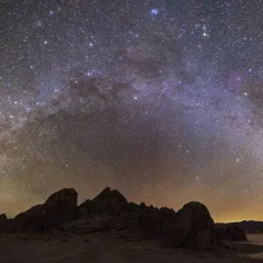 a bright halo of stars over a dark landscape 