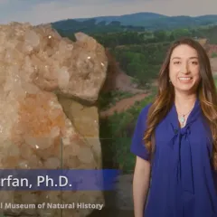 Gabriela Farfan, a woman with long, brown hair and a blue shirt, standing next to a block of quartz crystals slightly taller than she is
