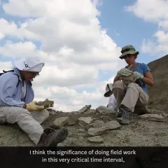 Two scientists on the top of a hill looking at two pieces of rock