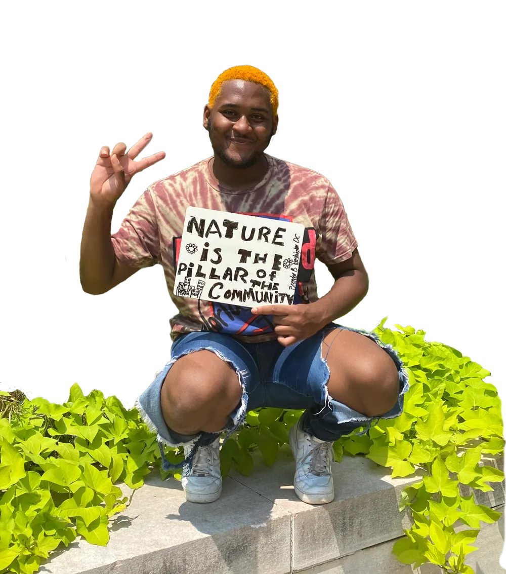 African American man with orange hair holding a peace sign with fingers and a sign that says nature is the pillar of the community