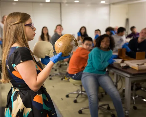A museum educator holds up two models of human skulls during a school program in Q?rius.