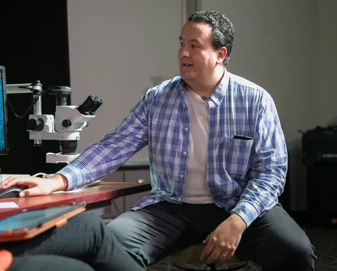 Juan Pablo Hurtado Padilla sitting at a microscope.