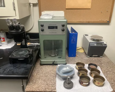 A scale, mortar and pestle, and sieves on a speckled countertop