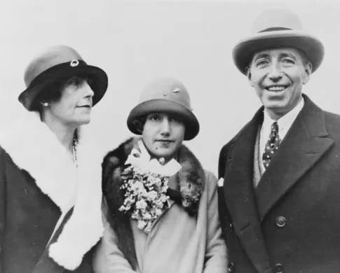 Three light-skinned people in brimmed hats and coats