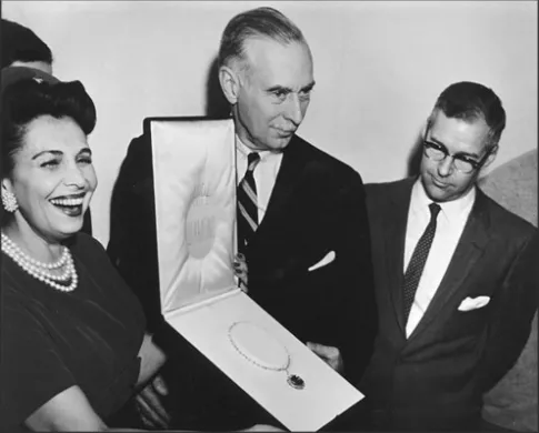 A smiling woman beside two men in suits, one of whom holds the Hope Diamond