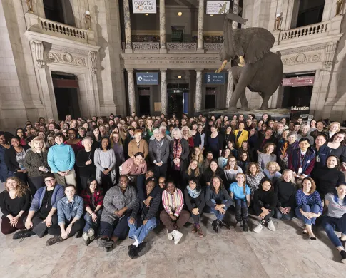 A group photo in the rotunda of museum in front of the elephant with all women who work in the museum