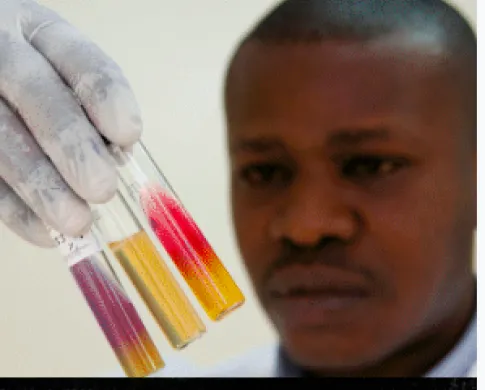 a man holding up three viles of red and yellow 