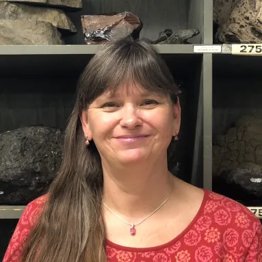 Woman in red shirt stands in front of shelves full of rocks