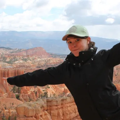 image of woman in black jacket and green hat in front of canyon