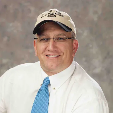 Lee A. Weigt wearing a white shirt and blue tie and an L.A.B. XXL baseball cap.