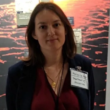 A woman with medium-light skin tone in front of a picture of lava
