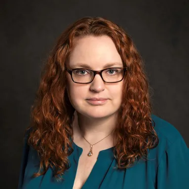 A red-haired woman with light skin tone in a teal shirt
