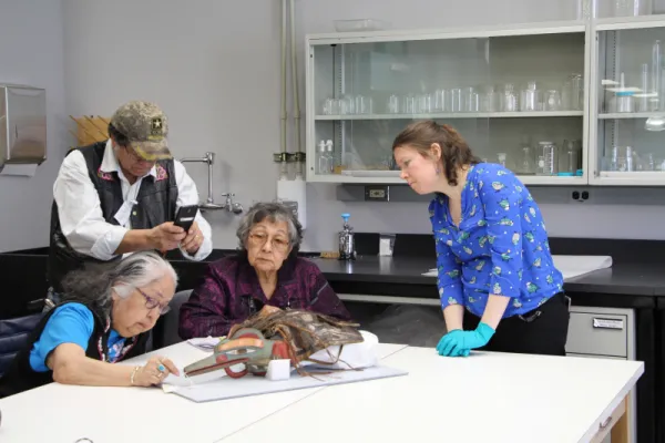 People contemplating metal on the beak of a Tlingit dance hat.