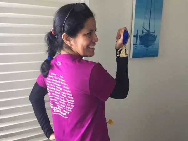 Gabriela Pérez Báez holding a marathon medal wearing a Stride for Thrive shirt.