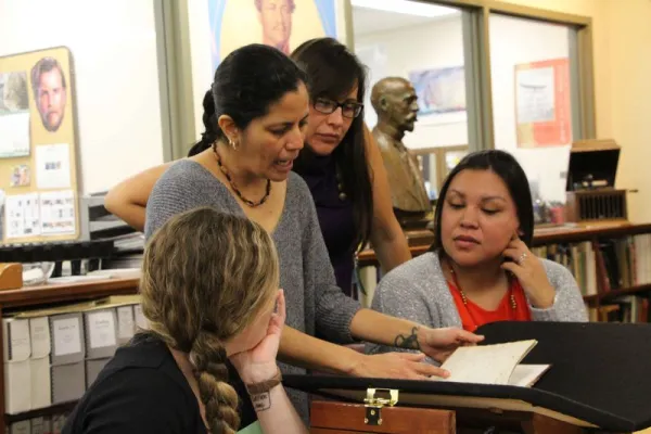 Four women discussing archival material.