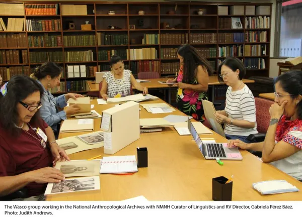 Group of people seating around a rectangular table looking at archival material.
