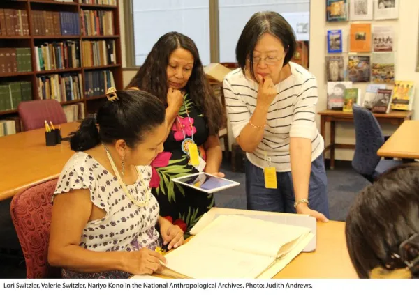Three women looking over archival documents.