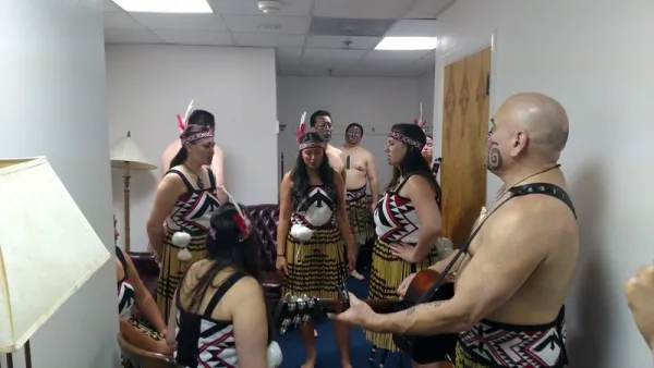 Māori group waiting backstage; women are in reed skirts.