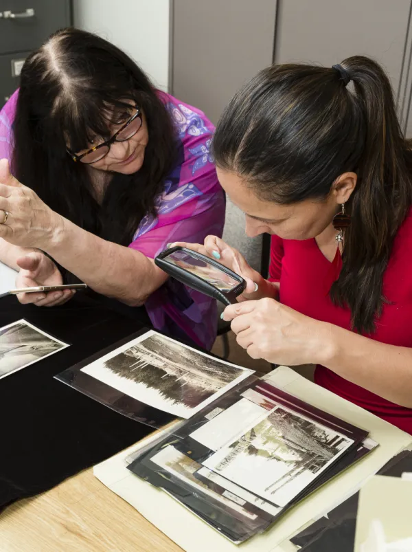 Two woman looking at images through a magnifying glass.