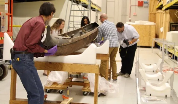 People lifting up a wa'a (canoe)