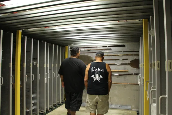 Two men looking at Polynesian paddles and staffs.