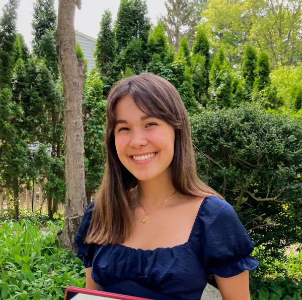 Annemarie Wood smiling for a portrait photo standing in front of trees