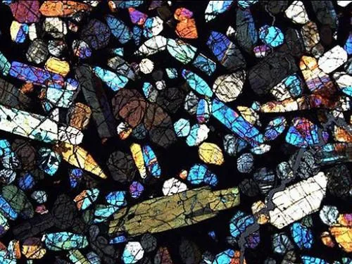 Brilliant mix of shapes colors like stained glass of a thin section of Antarctic meteorite.