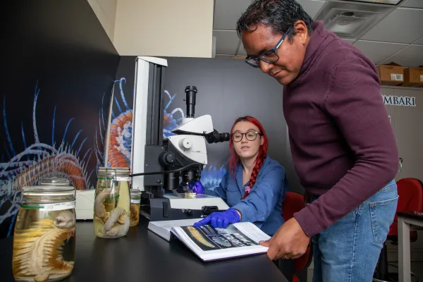 Victor Conde at a microscope with NHRE intern Soren Kite