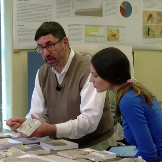Dr. Conrad Labandeira and Maggy Benson in his lab with various fossils on the table.