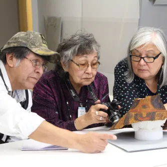 Tlingit community researchers examine traditional Tlingit hat in collections