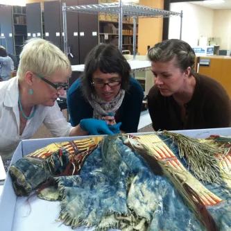 SIMA Students and faculty examining and discussing a Plains Indian shirt