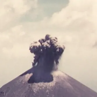 Image of large plume of dark ash emerging from the top of a volcano.