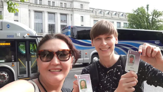 Two women show ID Badges in front of museum