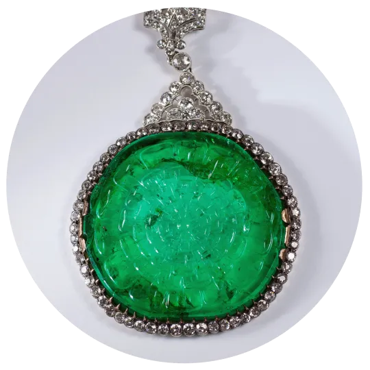 A round green gem surrounded by diamonds on a necklace. 