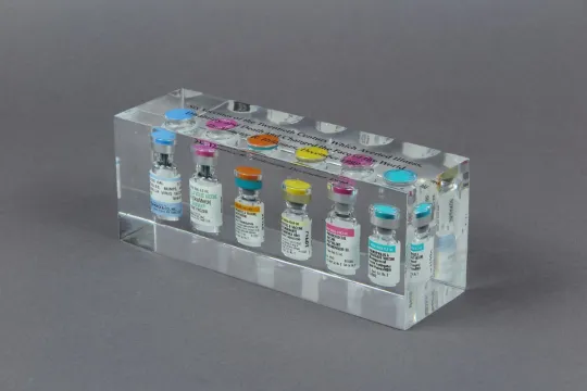 Transparent plastic box with six vaccine vials in it.