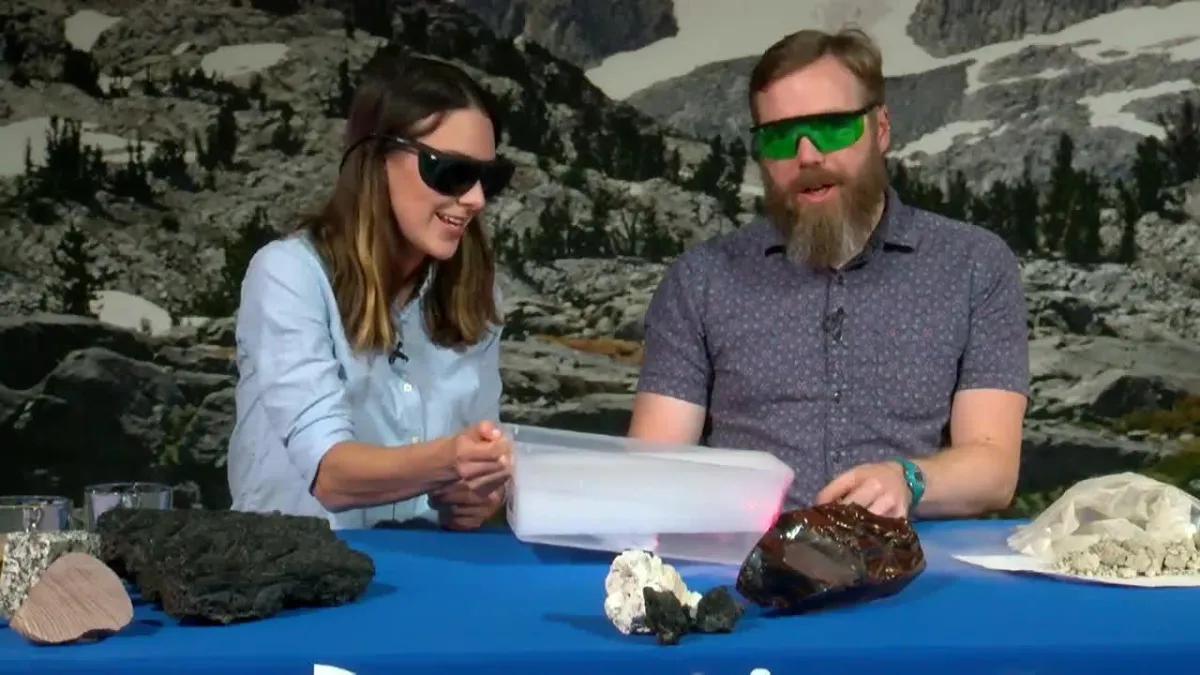 Geologist Ben Andrews and Maggy Benson at a table doing a demonstration with a tray of dry ice while wearing protective glasses.