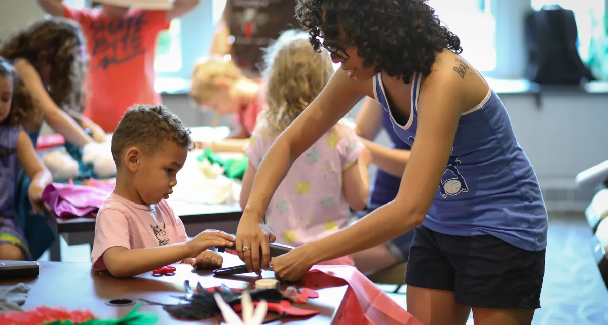 A mother and son construct a dinosaur costume together during a Natural History Museum family program