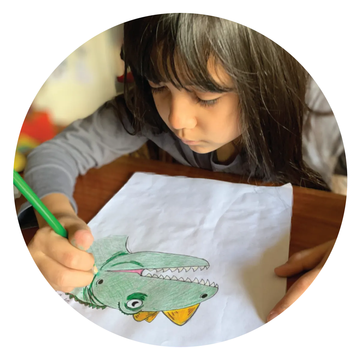 A girl coloring in a drawing of a dinosaur.