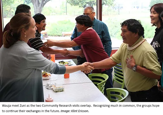People shaking hands across a table.