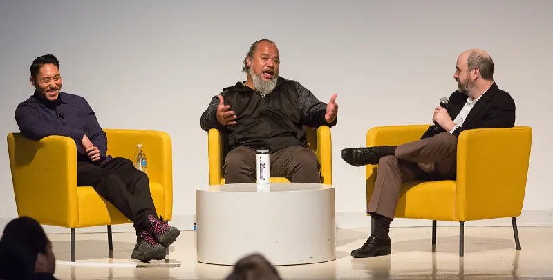 Three people sitting in yellow chairs talking to an off-screen audience.