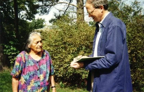 Man holding a book talking to an elderly woman.