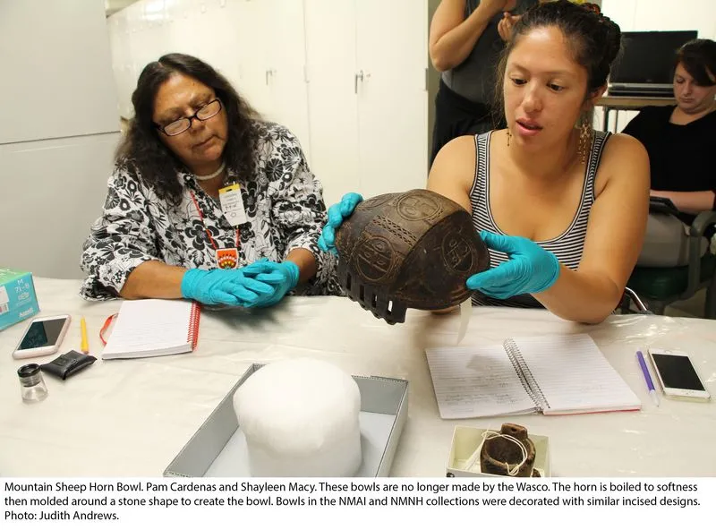 Two women examining a Mountain Sheep horn bowl.