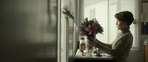 Still shot of a woman holding a vase of flowers from the film Loreak.