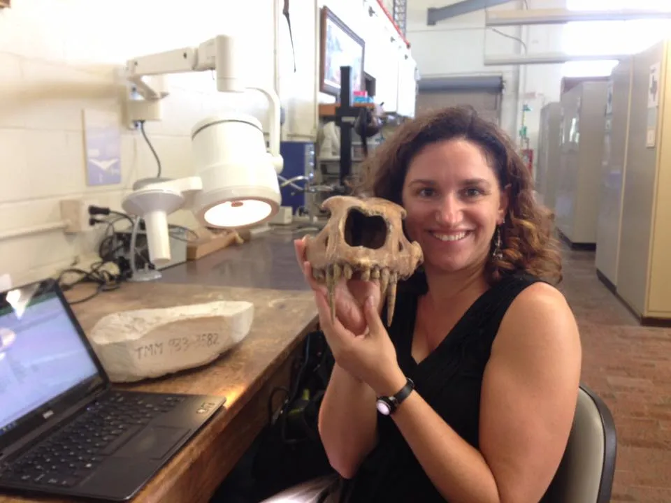 Briana in a lab holding the skull of a saber-toothed cat